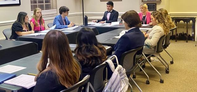 Teens debating government policies at a table.